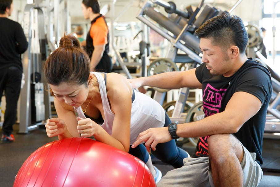 心と体を整える女性専門自己探求コーチ安沢明也がジムで対面パーソナルトレーニングで指導する様子